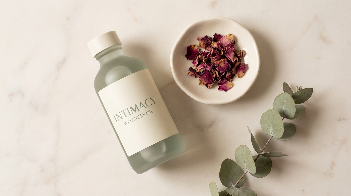 A frosted glass wellness oil bottle on marble with dried rose petals and eucalyptus